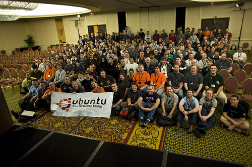 Group photo of attendees at an Ubuntu Developer Summit, posed in a hotel ballroom behind an Ubuntu banner.